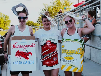 Participants dressed in Narragansett beer can costumes smiling at a themed race event